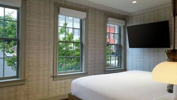 Habitación de hotel con una cama grande, un televisor de pantalla plana montado en la pared y ventanas amplias que ofrecen vistas al exterior.