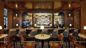 A bar area with multiple seating arrangements, a well-stocked bar counter, and ambient lighting.