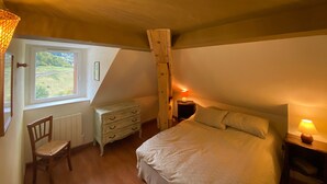 A bedroom with a large bed, a wooden dresser, a chair, a window with a view of greenery, and a sloped ceiling. - Bright apartment in Villard-de-Lans, 58 m², 2 bedrooms, near Vercors activities (Villard-de-Lans)