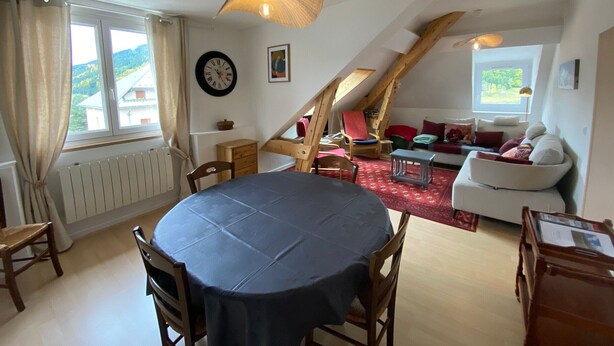 A cozy loft-style room with a dining table, chairs, a sofa, and a red carpet. - Bright apartment in Villard-de-Lans, 58 m², 2 bedrooms, near Vercors activities (Villard-de-Lans)