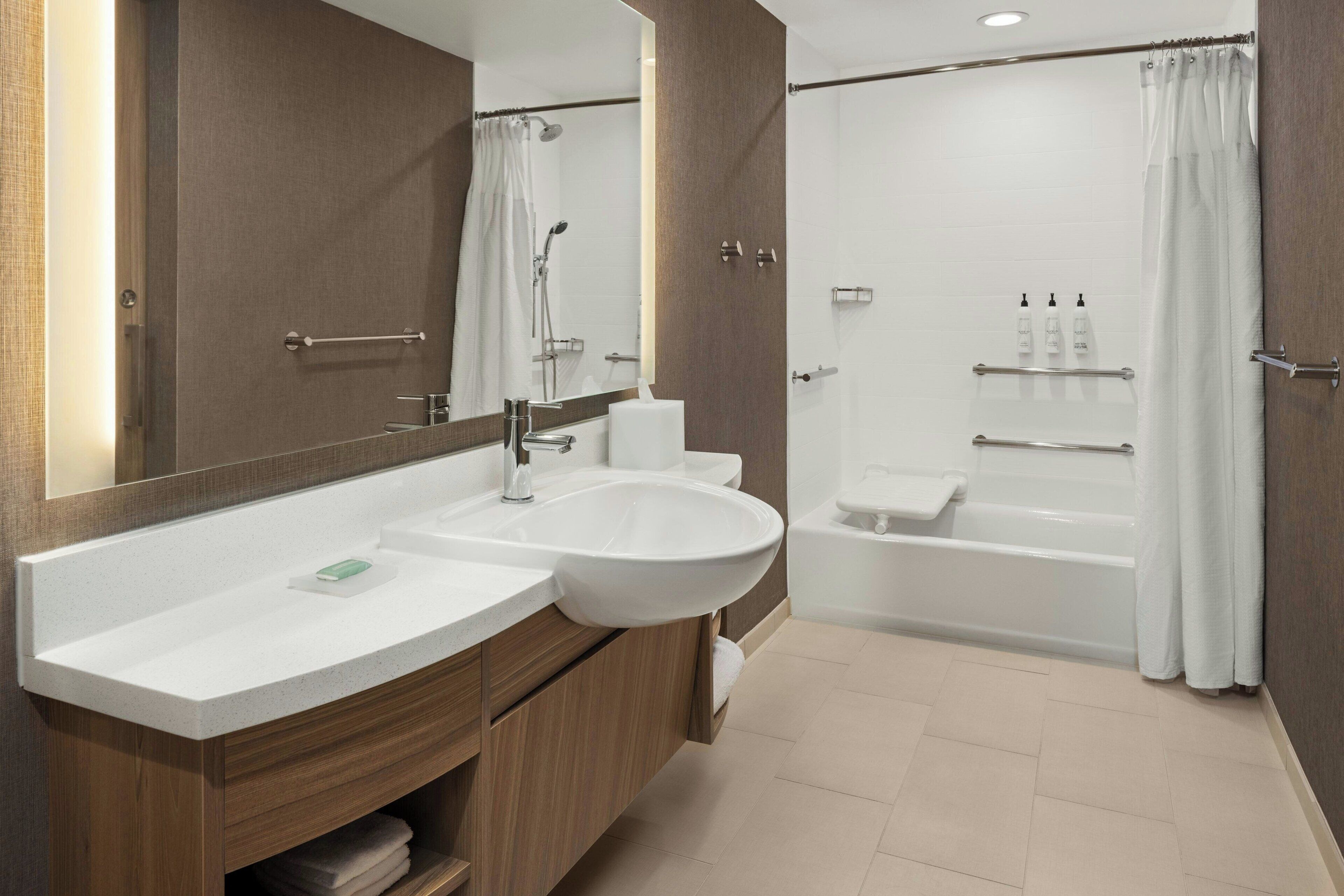 A modern bathroom with a large sink, mirror, and separate shower and bathtub area.