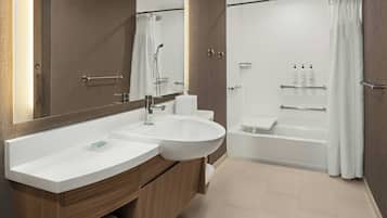 A modern bathroom with a large sink, mirror, and separate shower and bathtub area.