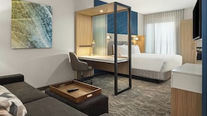 Une chambre d’hôtel moderne équipée d’un lit, d’un bureau, d’un canapé et d’une télévision.