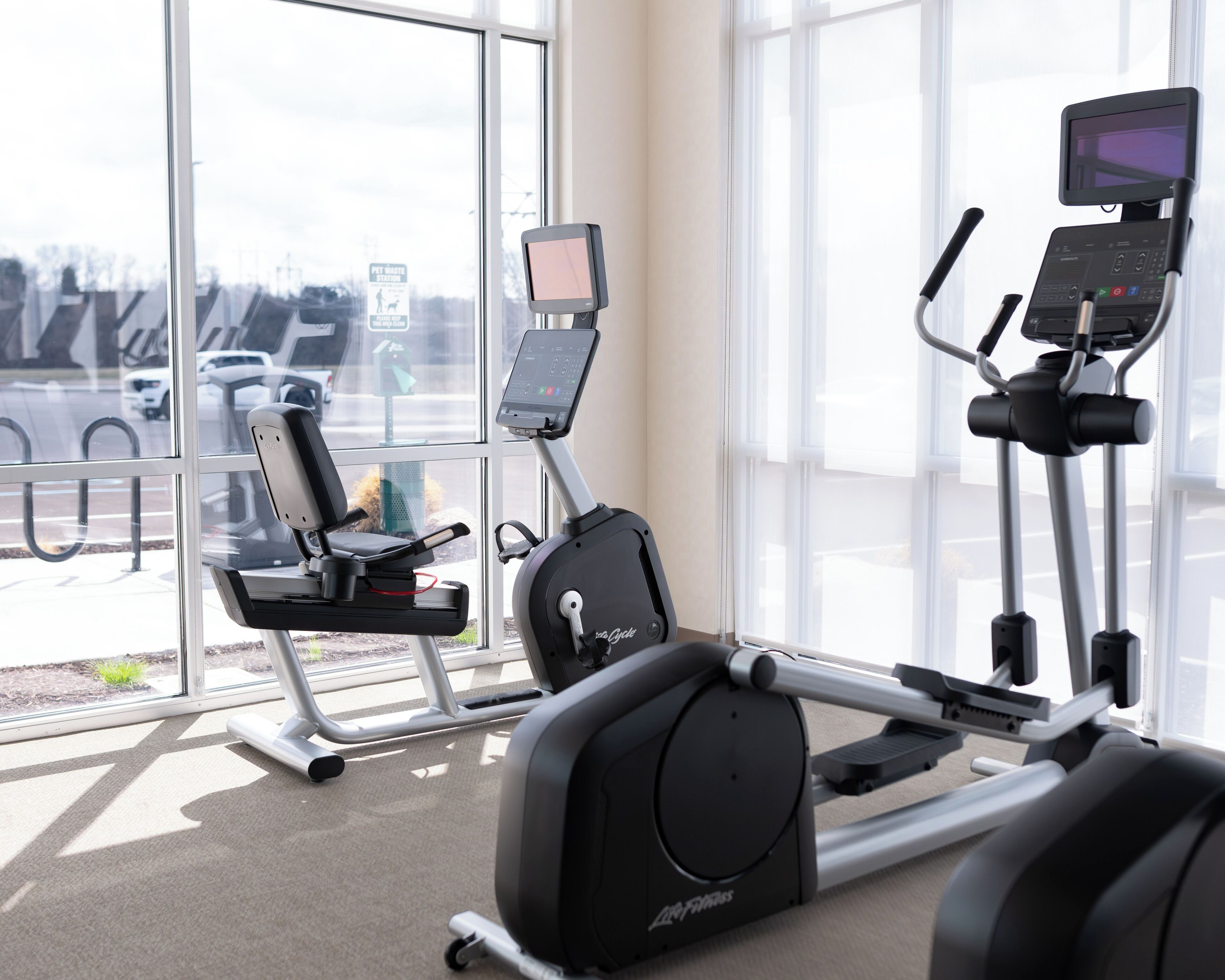 Une salle de sport intérieure équipée d’appareils de cardio-training, d’un tapis de course et d’un vélo elliptique.