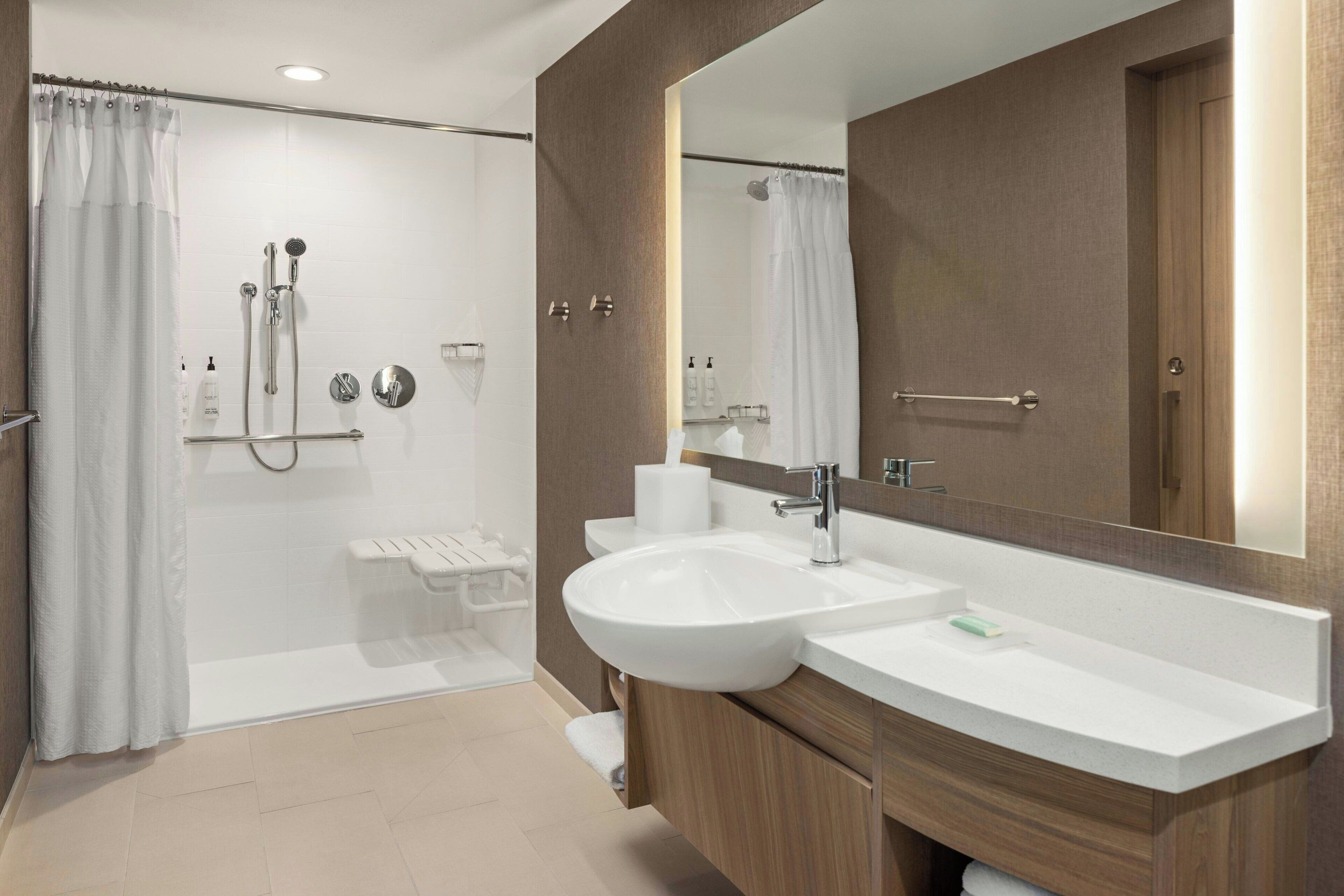 Une salle de bain moderne avec une douche à l’italienne, deux vasques, un grand miroir et des meubles en bois.