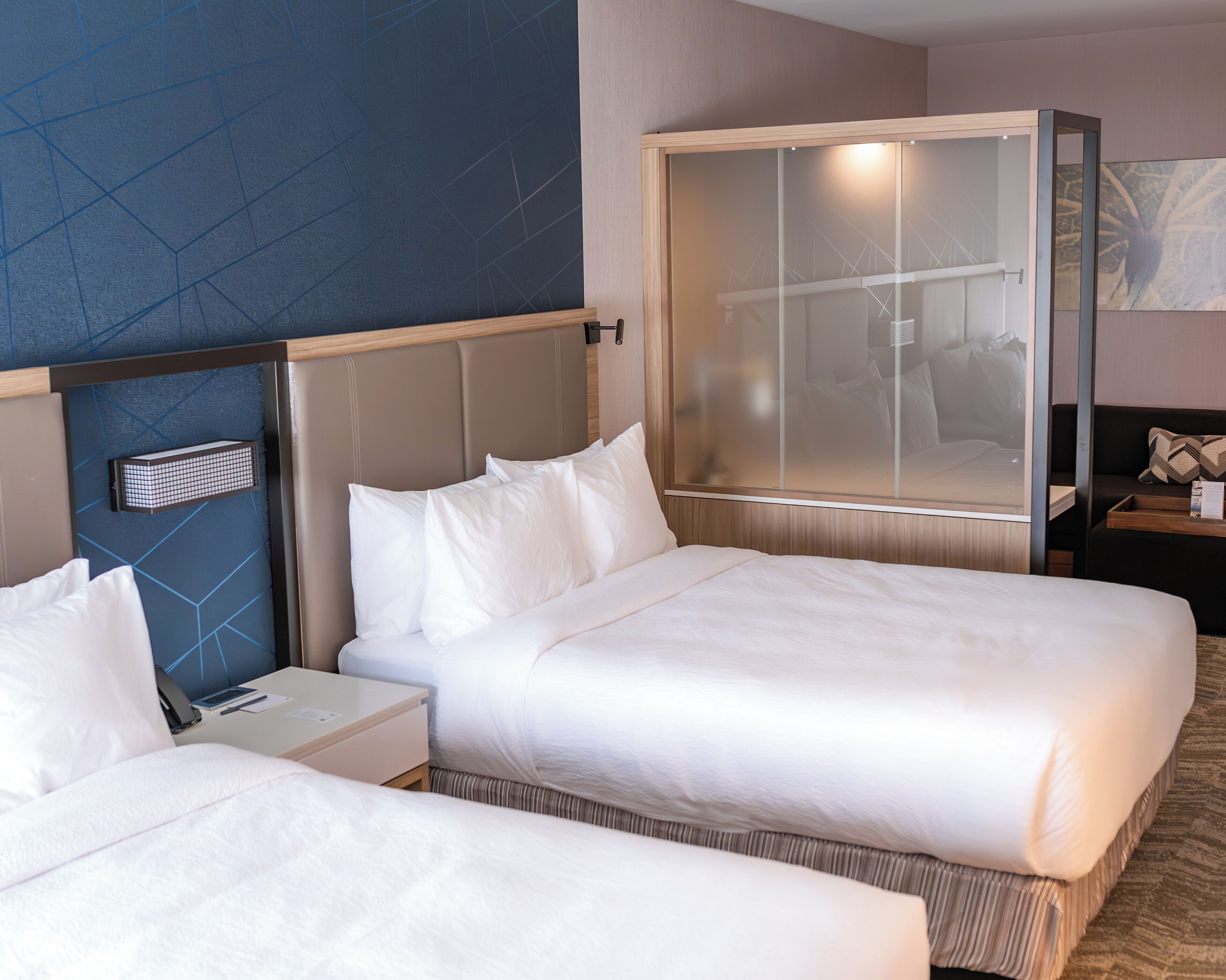 Une chambre d’hôtel avec deux lits, une grande fenêtre, une table de chevet et un radiateur fixé au mur.