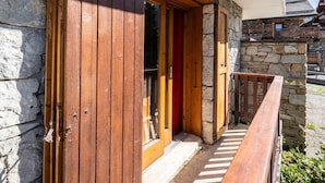 A wooden exterior with a stone wall, a wooden door, and a wooden balcony.