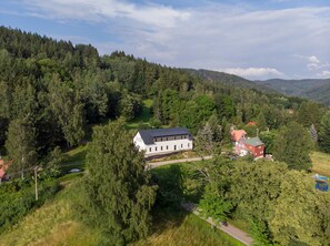 A large white building surrounded by dense forest, with a red-roofed structure nearby. - Villa in Desna Near Ski Resorts (Desna)