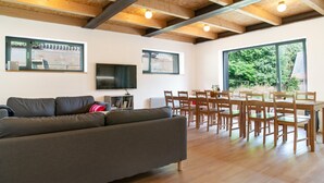Uma sala de estar moderna com sofá, televisão, mesa de jantar e cadeiras.