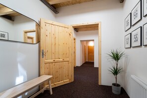 A hallway with wooden doors, a bench, a potted plant, and framed numbers on the wall. - Villa in Desna Near Ski Resorts (Desna)