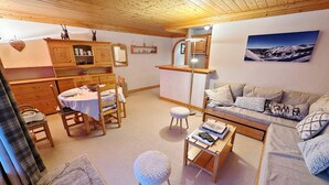 A cozy room with wooden furniture, a dining table, a sofa, and a view of a snowy landscape.