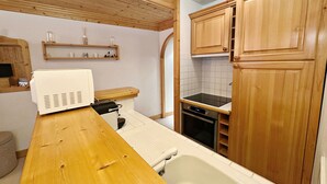 A kitchen with wooden cabinets, a countertop, a sink, and a stove.