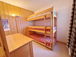 A bunk bed with a wooden desk and a poster on the wall.