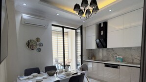 Een moderne keuken met witte kastjes, een marmeren aanrecht en een eethoek met een tafel gedekt voor vier personen.