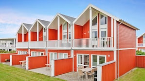 A red and white two-story building with balconies, outdoor seating, and a grassy yard. - 5 Star Holiday Home in Lokken (Lokken)