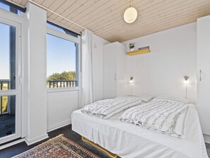 A bedroom with a bed, a window, a ceiling light, and a small shelf with a plant. - 5 Star Holiday Home in Lokken (Lokken)