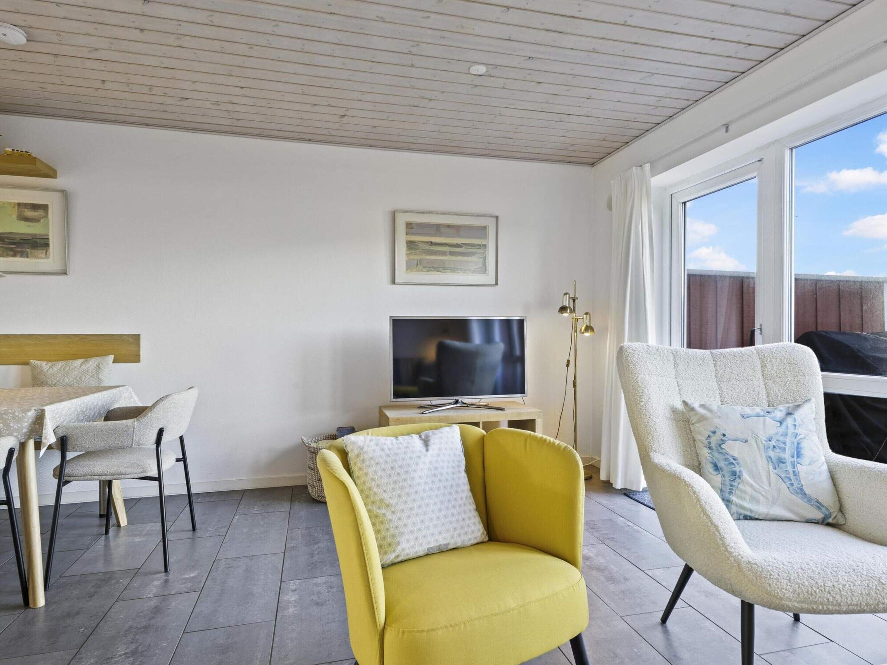 Ein modernes Wohnzimmer mit einer Couch, einem Sessel und einem Fernseher.