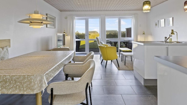 A modern kitchen with a dining area, large windows, and a view of the outdoors. - 5 Star Holiday Home in Lokken (Lokken)