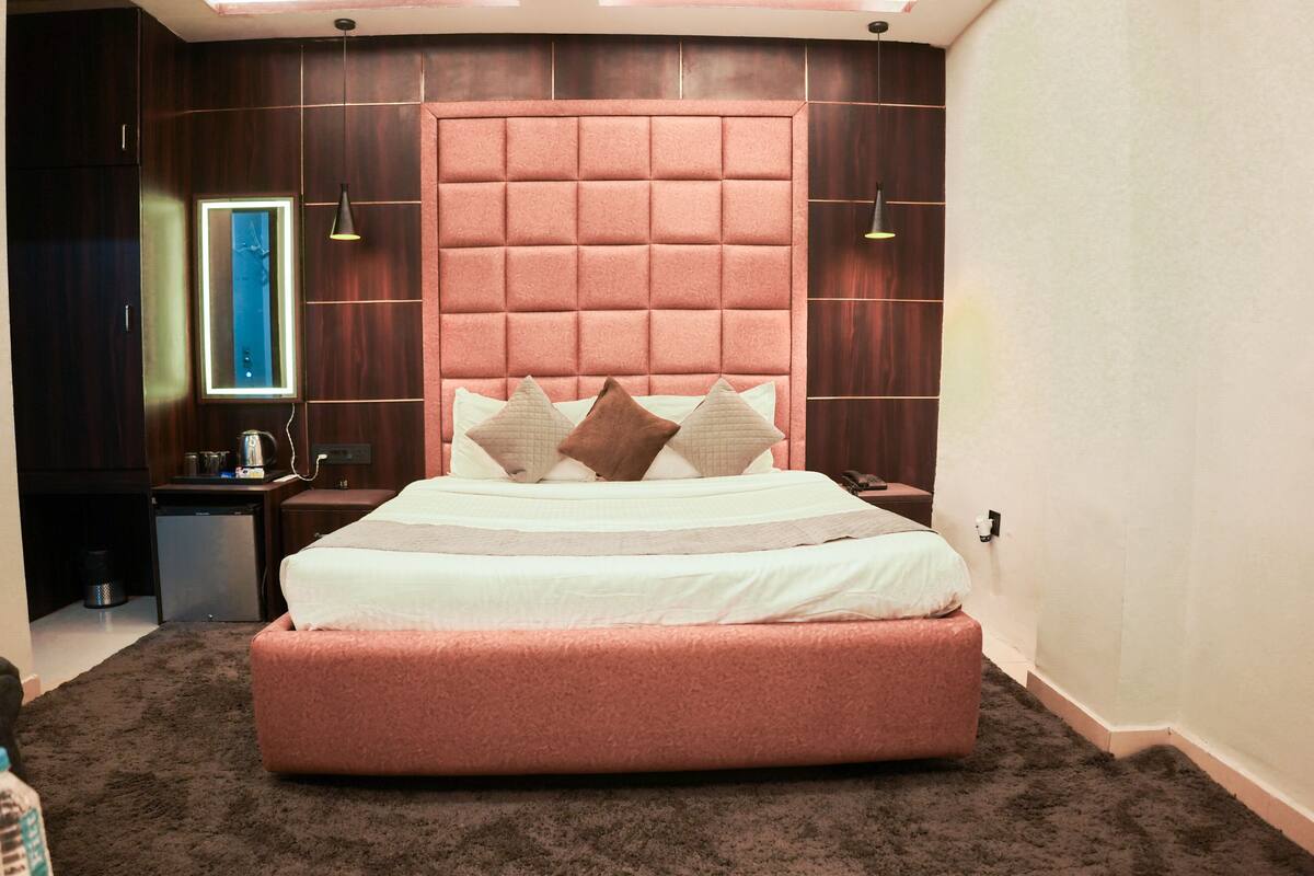 Un dormitorio con una cama grande, cabecera, mesita de noche y un pequeño escritorio.