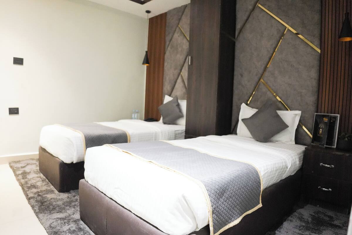 Un dormitorio moderno con dos camas, cabeceros de madera oscura y un diseño minimalista.