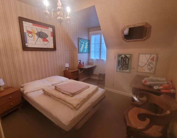 A bedroom with a bed, a desk, a chair, and artwork on the walls. - 3-bedroom house for 6 people (Authon-du-Perche)