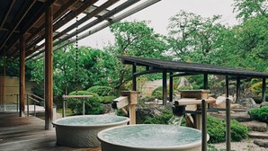 Un onsen japonais traditionnel, avec des passerelles en bois et des bains en pierre.