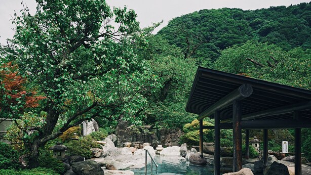 Un jardin japonais traditionnel avec un sentier de pierres, un petit étang et un pavillon en bois.