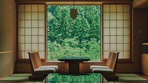 Une pièce de style japonais traditionnel, avec un sol recouvert de tatamis, une table basse et deux chaises.