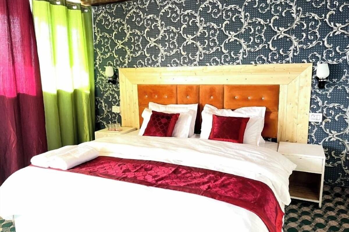 A bed with a wooden headboard, white bedding, and red pillows.