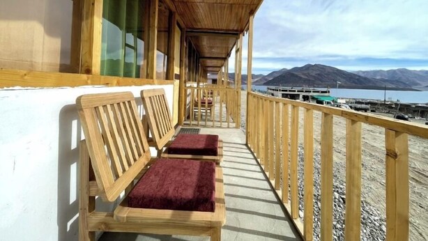 A wooden deck with benches and a view of a lake and mountains. - Ecstasy Huts Pangong (Leh)