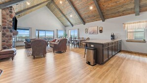 Een ruime woonkamer met een hoge plafond, stenen open haard en uitzicht op het landschap.