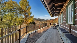 Un ponte di legno con ringhiera, una panchina e un edificio con tetto spiovente e finestre.