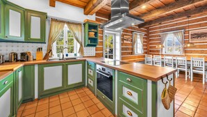 Una cucina con mobili verdi, un piano di lavoro in legno, una cappa aspirante in acciaio inossidabile e un pavimento piastrellato.