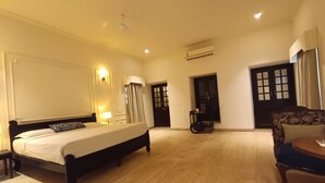 Een hotelkamer met een groot bed, een bureau, een stoel, een kledingkast en een airconditioning.