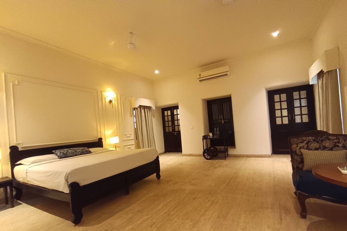 Quarto de hotel com cama grande, escrivaninha, cadeira, guarda-roupa e ar condicionado.
