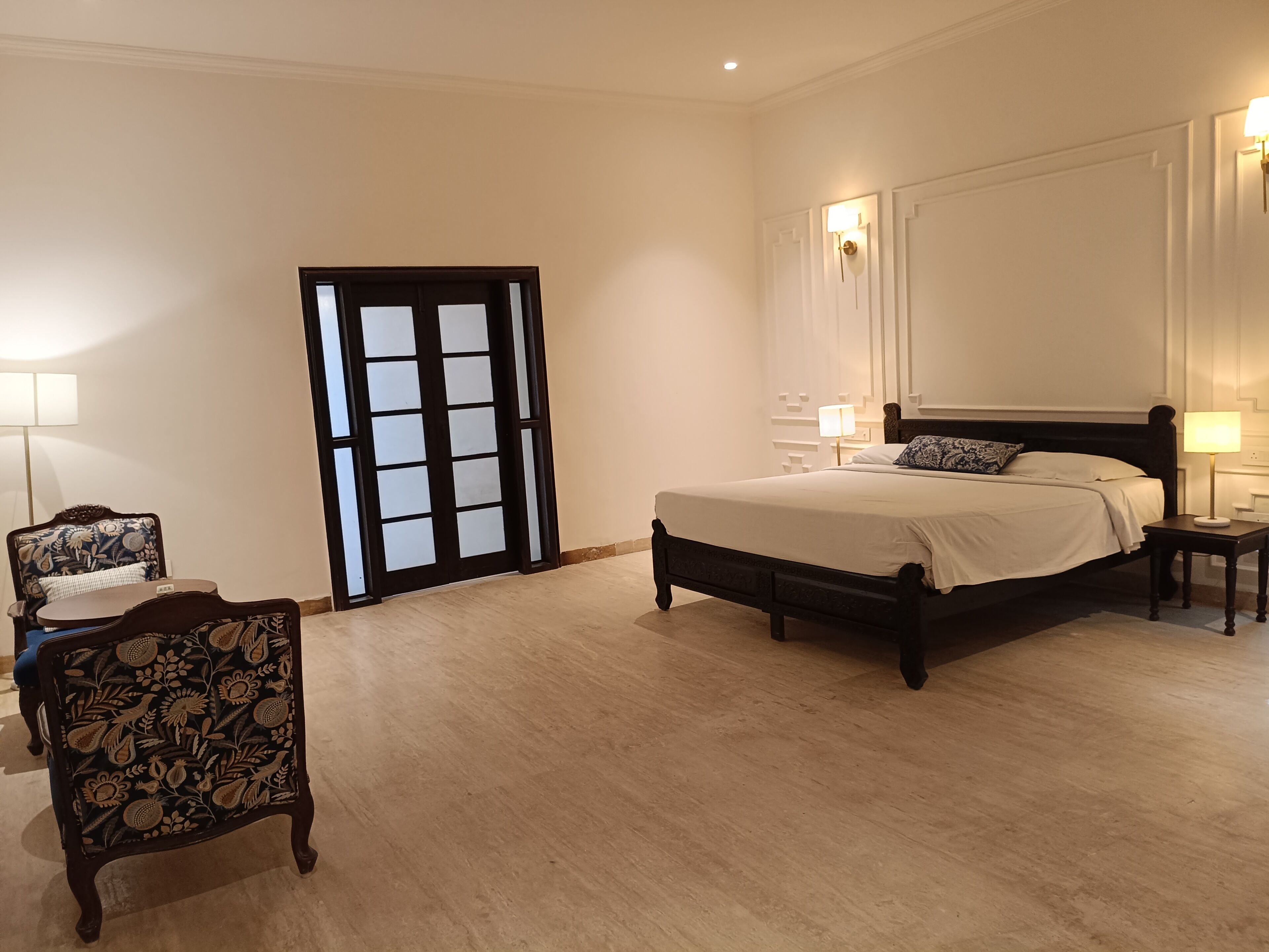A bedroom with a bed, a chair, a nightstand, and a door.