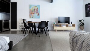 A modern living room with a dining area, a large TV, and a zebra painting on the wall. - Bright Studio in Launceston CBD (Launceston City)