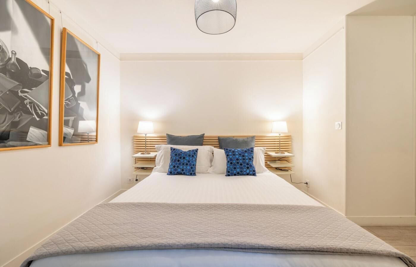 Habitación de hotel con una cama grande, dos mesitas de noche con lámparas y una obra de arte en la pared.