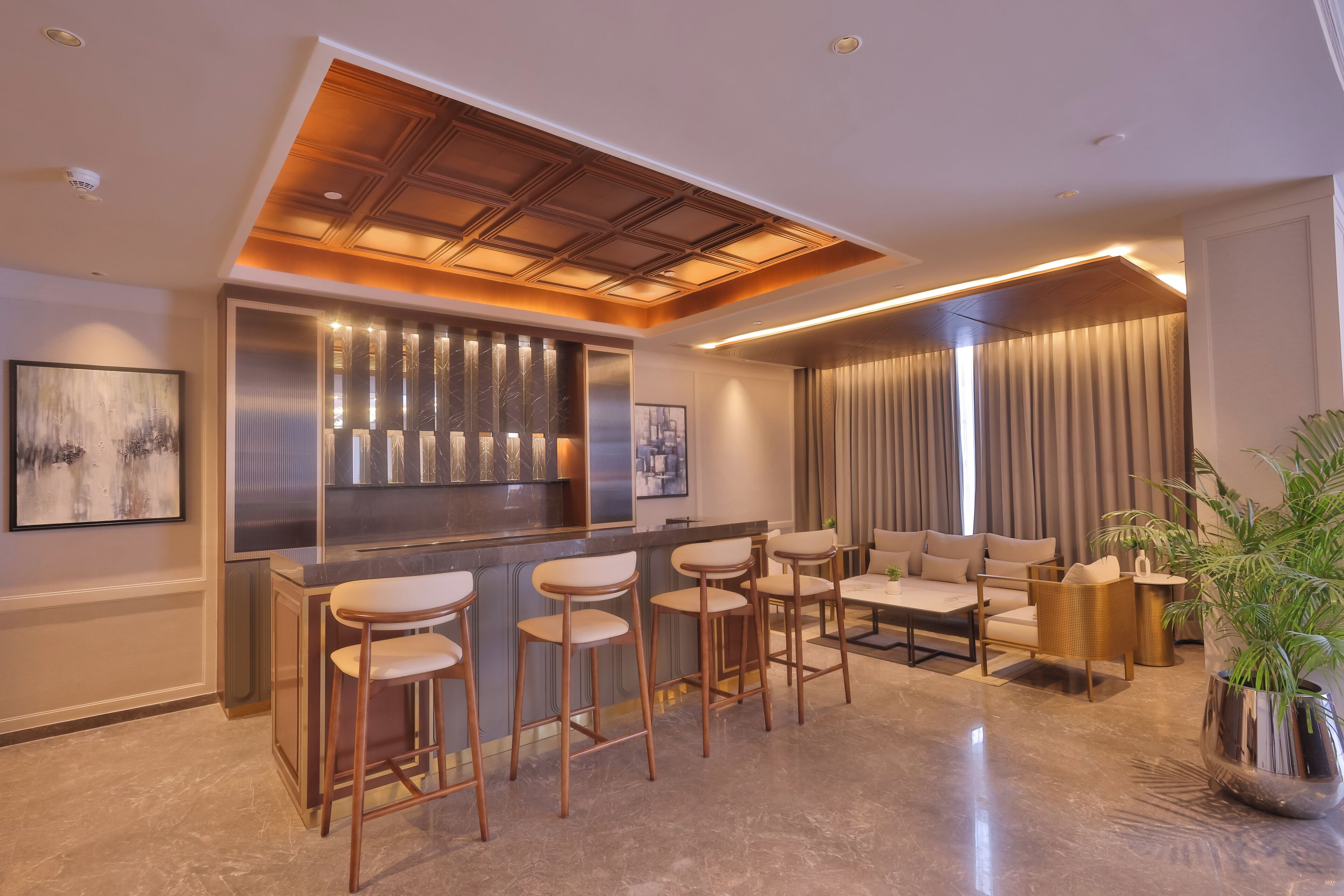 A modern kitchen with a bar area, bar stools, and a seating area with a sofa and chairs.