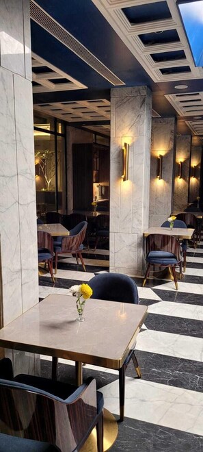 Een modern restaurantinterieur met marmeren vloer, donkerhouten tafels en stoelen.