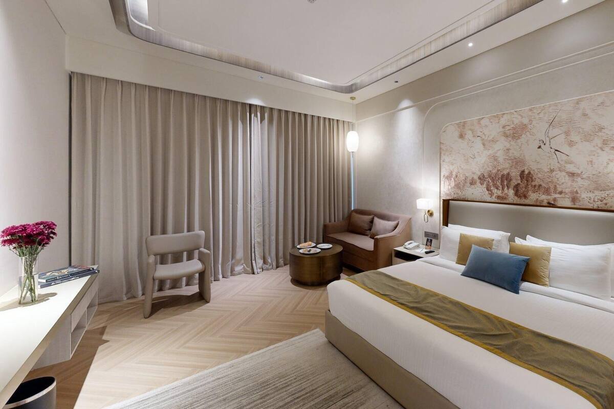 Une chambre d’hôtel moderne, dotée d’un grand lit, d’un bureau, d’une chaise et d’un grand tableau abstrait accroché au mur.