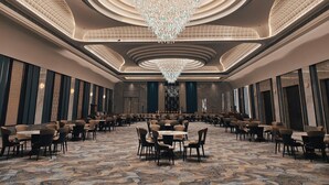 A spacious banquet hall with a large chandelier, tiered seating, and a patterned carpet. - The Tivoli New Delhi (New Delhi)