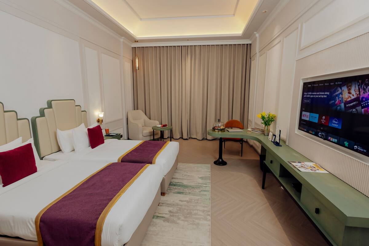 Une chambre d’hôtel avec deux lits, une télévision, un bureau et une chaise.
