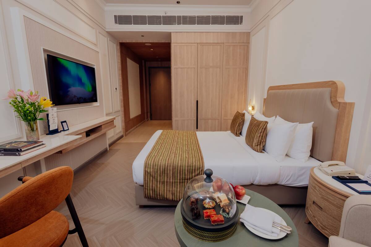 Une chambre d’hôtel comprenant un lit, un bureau avec un ordinateur, une télévision et un coin repas avec une table et des chaises.
