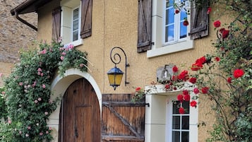 Un bâtiment rustique avec une façade en pierre, une porte en bois et une jardinière ornée de roses rouges.