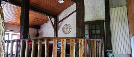 A wooden staircase with a railing, a clock on the wall, and a window with blinds.