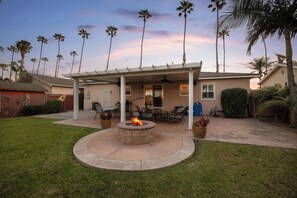 A patio with a fire pit, outdoor furniture, and a covered area with a ceiling fan. - Walk to the Beach! Private Backyard and Fire Pit (Oceanside)