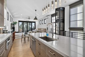 Uma cozinha moderna com uma ilha grande, eletrodomésticos de aço inoxidável e iluminação pendente.