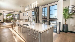 Una cocina espaciosa con una isla grande, elegantes lámparas colgantes y vistas al exterior.