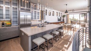 Una cocina moderna con electrodomésticos de acero inoxidable, una isla grande con taburetes y un comedor con vistas.
